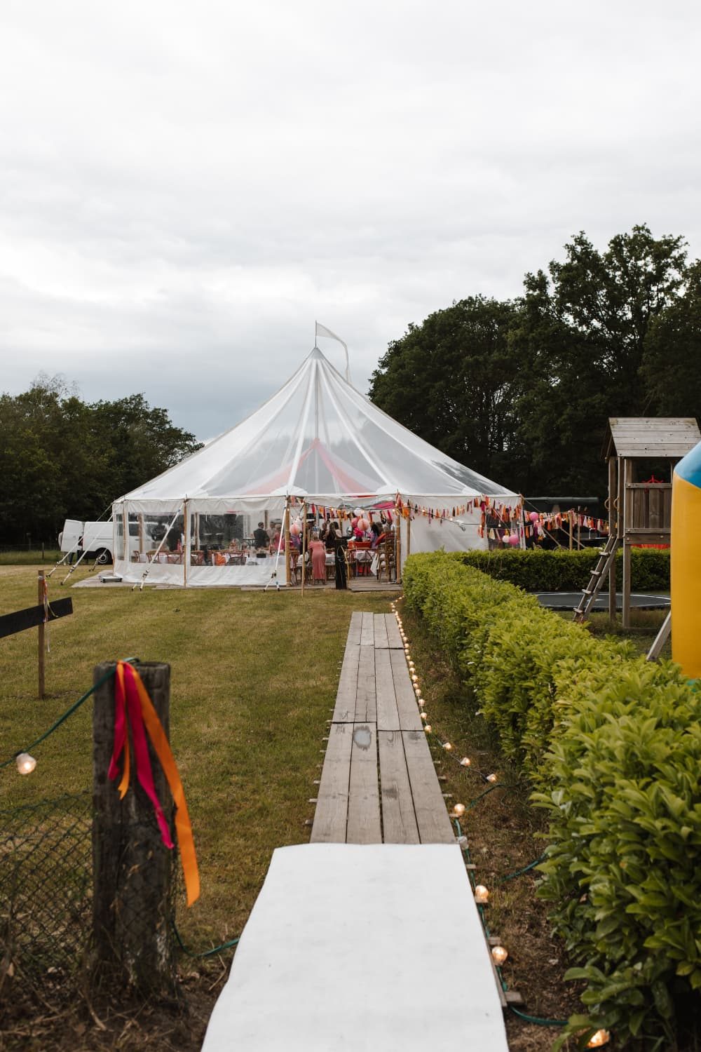 Pad naar een witte feesttent tussen de hagen